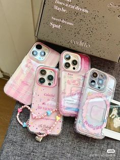 four pink cases sitting on top of a table next to a cell phone and necklace