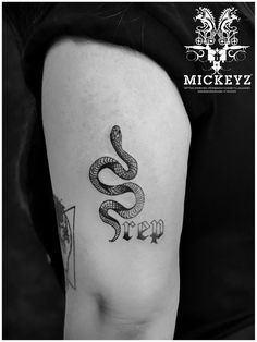 a black and white photo of a snake tattoo on the thigh, with words written in cursive writing