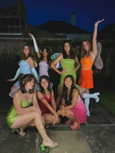 a group of young women dressed in fairy costumes posing for a photo outside at night