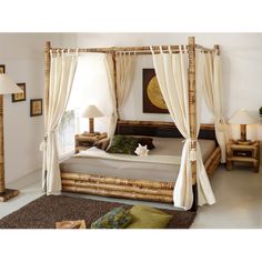 a bamboo bed with curtains and pillows in a white room next to two lamps on either side of the bed