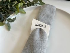 a plate with a napkin on it and a place card attached to the edge that says nattalia