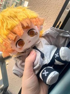 a hand holding a doll with yellow hair