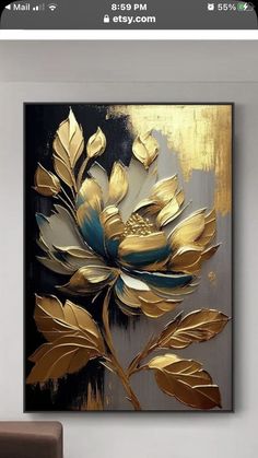 a gold and black flower painting on a wall in a room with a brown chair