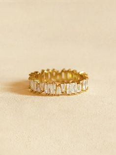 a close up of a gold ring on a white surface with small stones in the middle