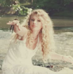 a woman sitting in the water with her arms outstretched