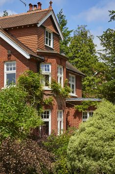 a red brick house surrounded by trees and bushes