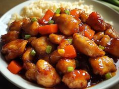 a white plate topped with chicken and vegetables on top of cauliflower next to rice