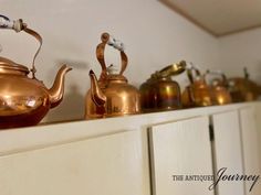 tea pots and kettles lined up on a shelf