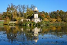 an old building sits in the middle of a lake surrounded by trees and water lilies