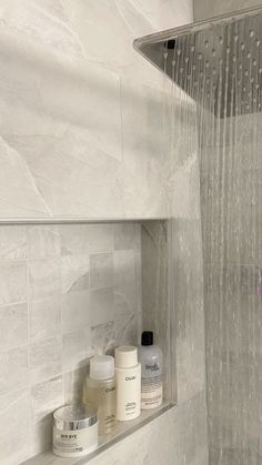 a shower head with water running down it's side and bottles on the shelf