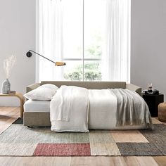 a bed sitting on top of a wooden floor next to a white wall and window