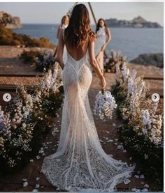 the back of a woman's dress as she walks down a path with flowers