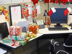 an office cubicle decorated for christmas with presents on the desk