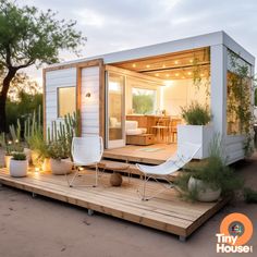 a tiny house is sitting on a wooden platform surrounded by plants and potted cacti