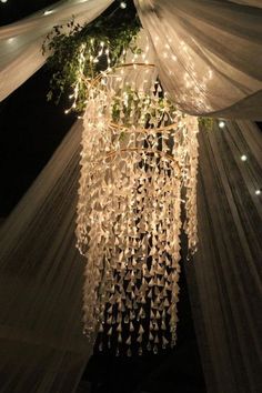 a chandelier hanging from the ceiling in front of a white canopy with lights on it