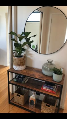 a mirror sitting on top of a wooden shelf next to a potted plant and books