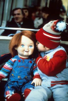 two dolls sitting next to each other in front of a group of people on a bus