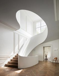 a white spiral staircase in a large room with hardwood flooring and wall paneling