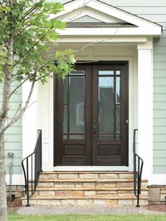 the front door of a house with black wrought iron railings and glass doors on either side