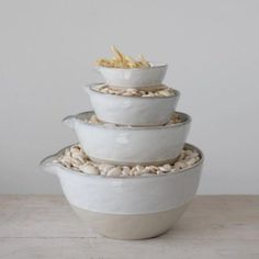 three white bowls stacked on top of each other with food in the bottom one bowl