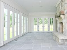 an empty room with white doors and windows on either side of the door is a stone bench