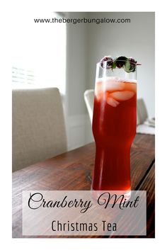 a tall glass filled with cranberry mint christmas tea on top of a wooden table