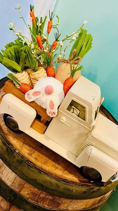 a toy truck with carrots and other vegetables in it on top of a barrel