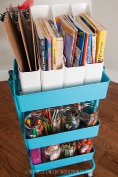 a blue cart filled with lots of books on top of a wooden floor