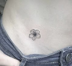 a woman's stomach with a small flower tattoo on the side of her belly