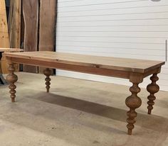 a wooden table sitting in a room next to a white wall and some wood planks