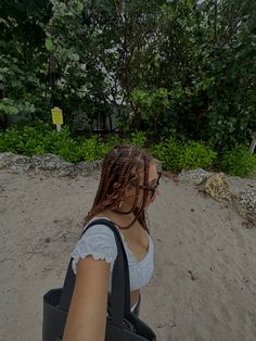 a woman with braids is sitting in the sand