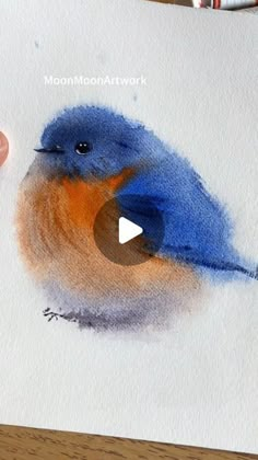 someone is painting a blue bird with watercolors on paper and then it looks like he's holding something in his hand