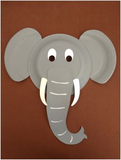 a paper plate elephant with eyes on it's head is hanging on the wall