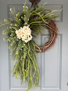 a wreath with white flowers and greenery hangs on the front door's gray door