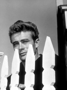 a man standing behind a white picket fence