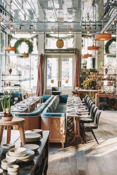 the inside of a restaurant with long tables and blue couches in front of windows