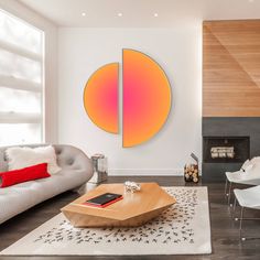 a modern living room with white furniture and wood paneled walls, along with a large circular painting on the wall