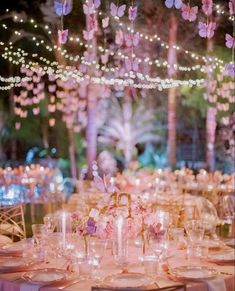 the tables are set up with pink flowers and lite - up lights in the background