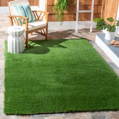 an outdoor area with green grass and potted plants on the side of the house