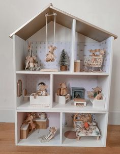 a white doll house with teddy bears and other items on the shelves in front of it