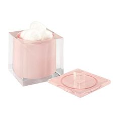 a pink glass container with cotton in it next to a square shaped object on a white background