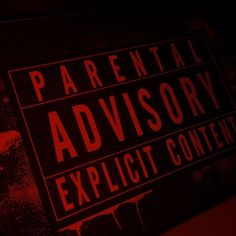 a sign that says parental advisory and explicit content on the side of a wall in a dark room