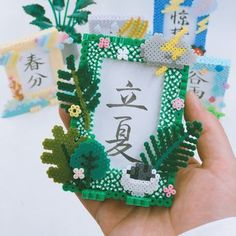 a hand holding a small green and white photo frame