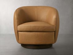 a tan leather swivel chair sitting on top of a cement floor next to a wall