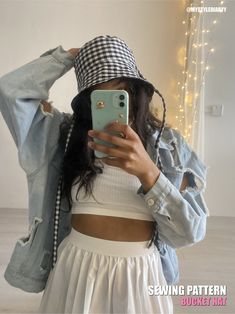 a woman taking a selfie in front of a mirror wearing a denim jacket and white skirt