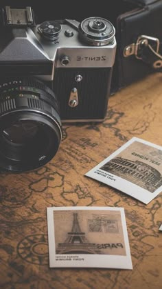 an old camera sitting on top of a table next to some paper and pictures with the eiffel tower in it