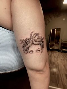 a woman's arm with a tattoo on it that has a snake wrapped around her head