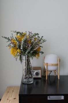 a vase filled with yellow flowers sitting on top of a table next to a radio