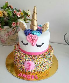 a birthday cake decorated with sprinkles and a unicorn face