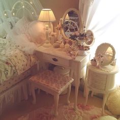 a bedroom with white furniture and pink flowers on the bed, two small stools